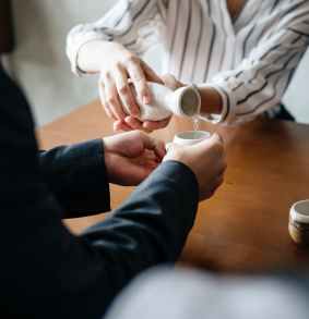 person pouring liquid to another persons cup