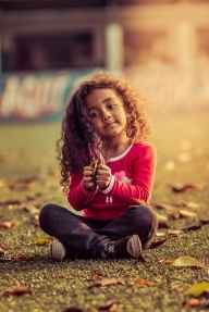 photo of kid playing with fallen leaves